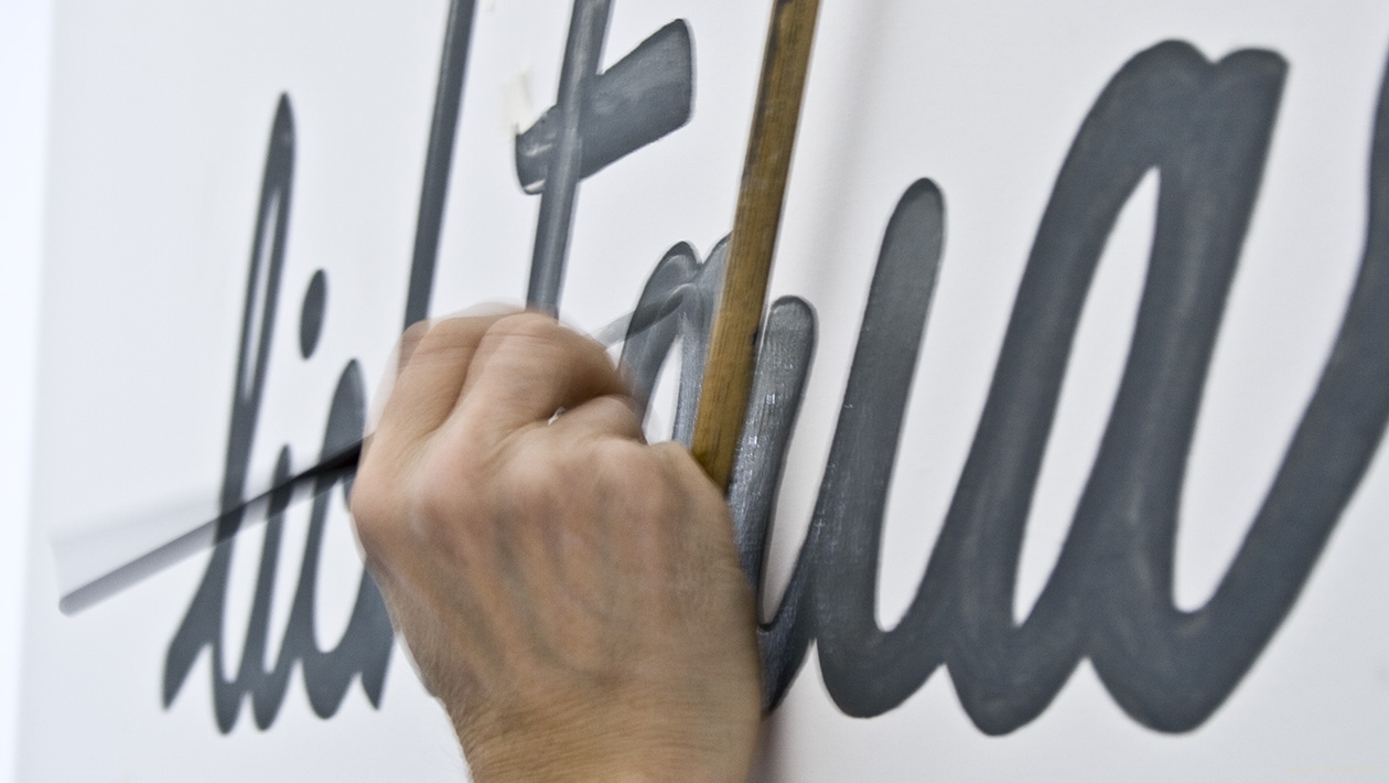 Detailfoto einer Hand beim Malen eines Logoschriftzugs